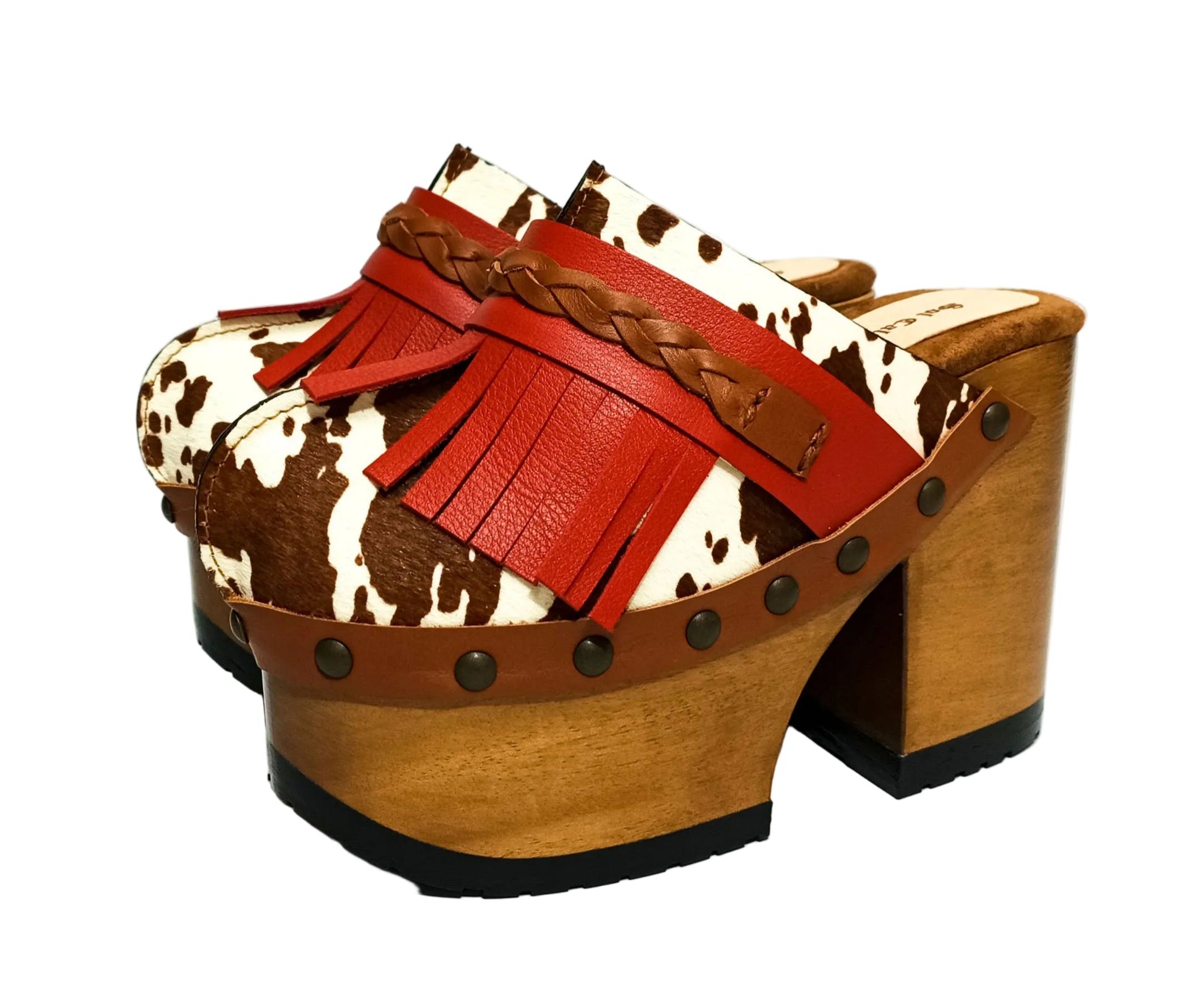 Verona Clogs by Sol Caleyo featuring light brown cow hair leather, red fringe details, and old gold studs on a high wooden platform sole with tractor grip.