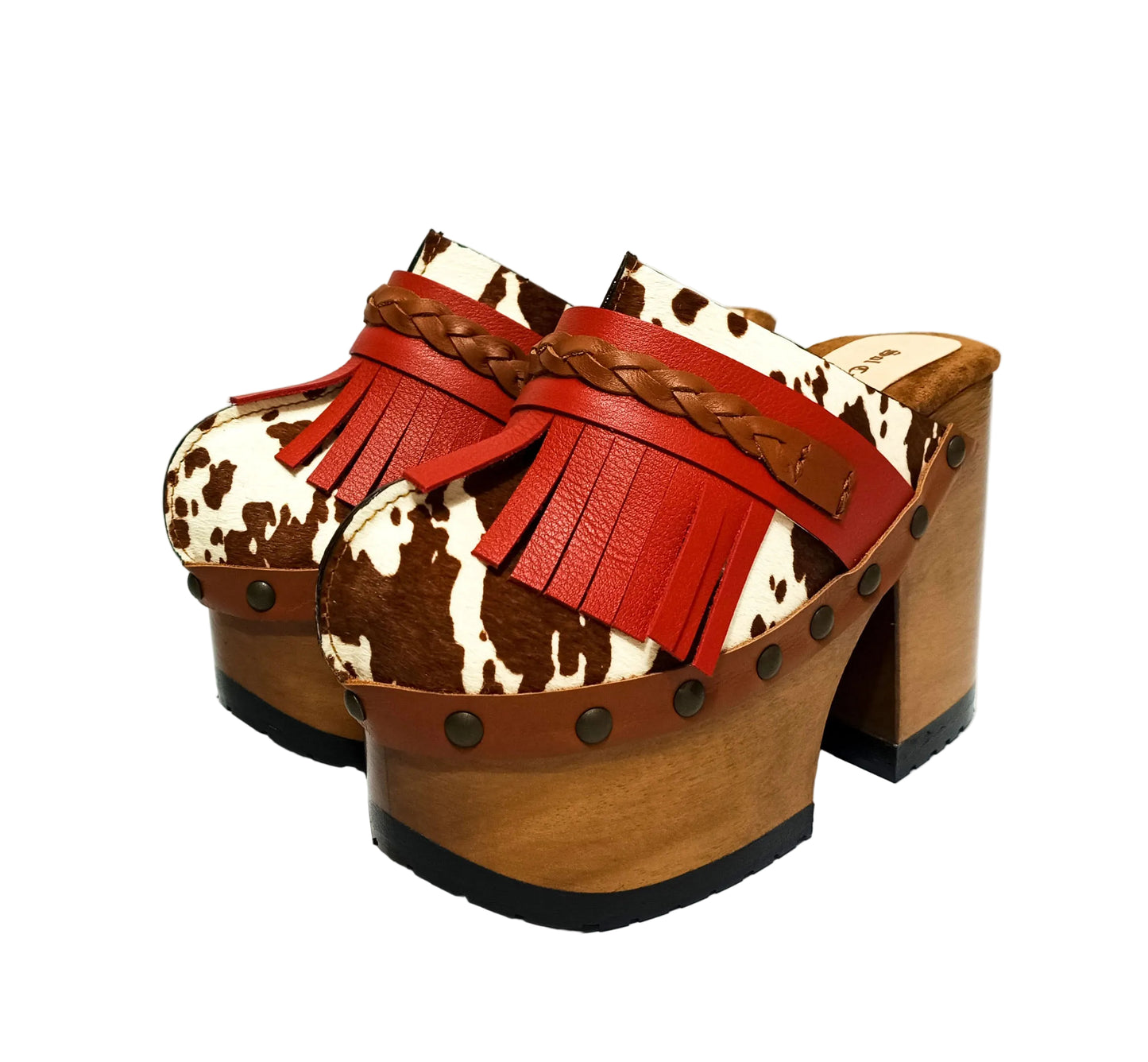 Verona Clogs by Sol Caleyo featuring light brown cow hair leather, red fringe details, and old gold studs on a high wooden platform sole with tractor grip.