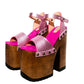 Handmade Crazy Pink metallic leather platform sandals by Sol Caleyo featuring old gold studs, a dark wood platform, and an 17 cm heel on a white background.