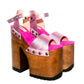 Handmade Crazy Pink metallic leather platform sandals by Sol Caleyo featuring old gold studs, a dark wood platform, and an 17 cm heel on a white background.
