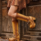 Beige handmade leather platform boots with fringe, coins, horns and shells on a 10 cm wooden heel by Sol Caleyo.