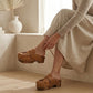 Close-up of the Niza tan leather platform clogs by Sol Caleyo, featuring hand-braided straps, fringes, and bronze studs on a carved wooden sole.
