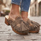 Model wearing Artemisa Earth Tone Suede Tassel Clogs with wooden platform and crochet details outdoors