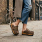 Woman walking in Sol Caleyo aged brown leather platform clogs with antique brass buckle on a cobblestone street