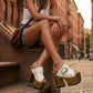 Model wearing custom-made White Western Sandals, highlighting the artisanal wood craftsmanship and extreme platform height in an urban setting.