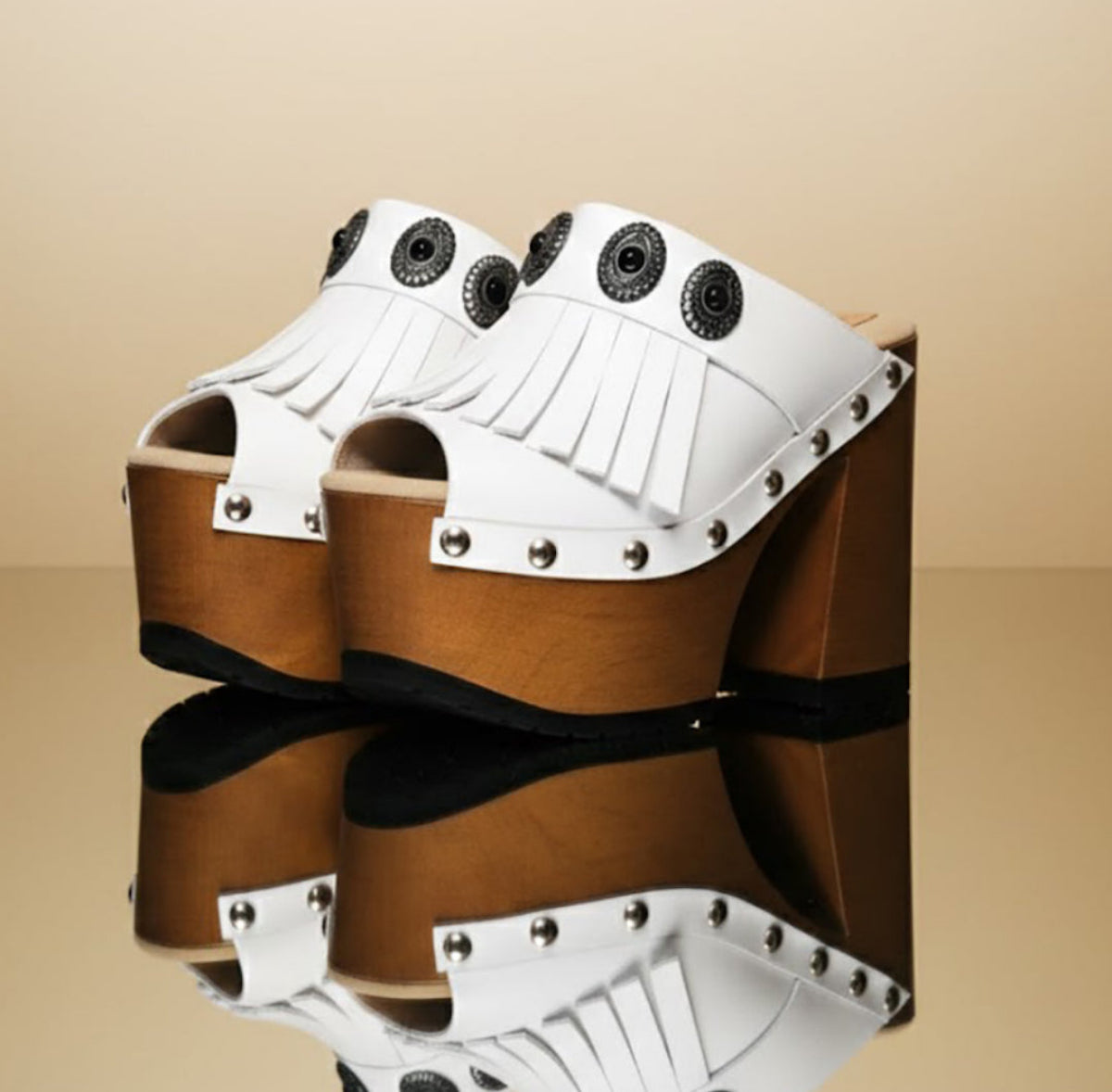 White handmade leather boho platform mule sandals with fringe, silver conchos and 14 cm wooden heel by Sol Caleyo