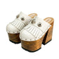Side view of White Indian Clogs XL featuring extreme 17cm natural wood platform, white leather fringes, and antique silver metal conchos.