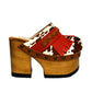 Verona Clogs by Sol Caleyo featuring light brown cow hair leather, red fringe details, and old gold studs on a high wooden platform sole with tractor grip.