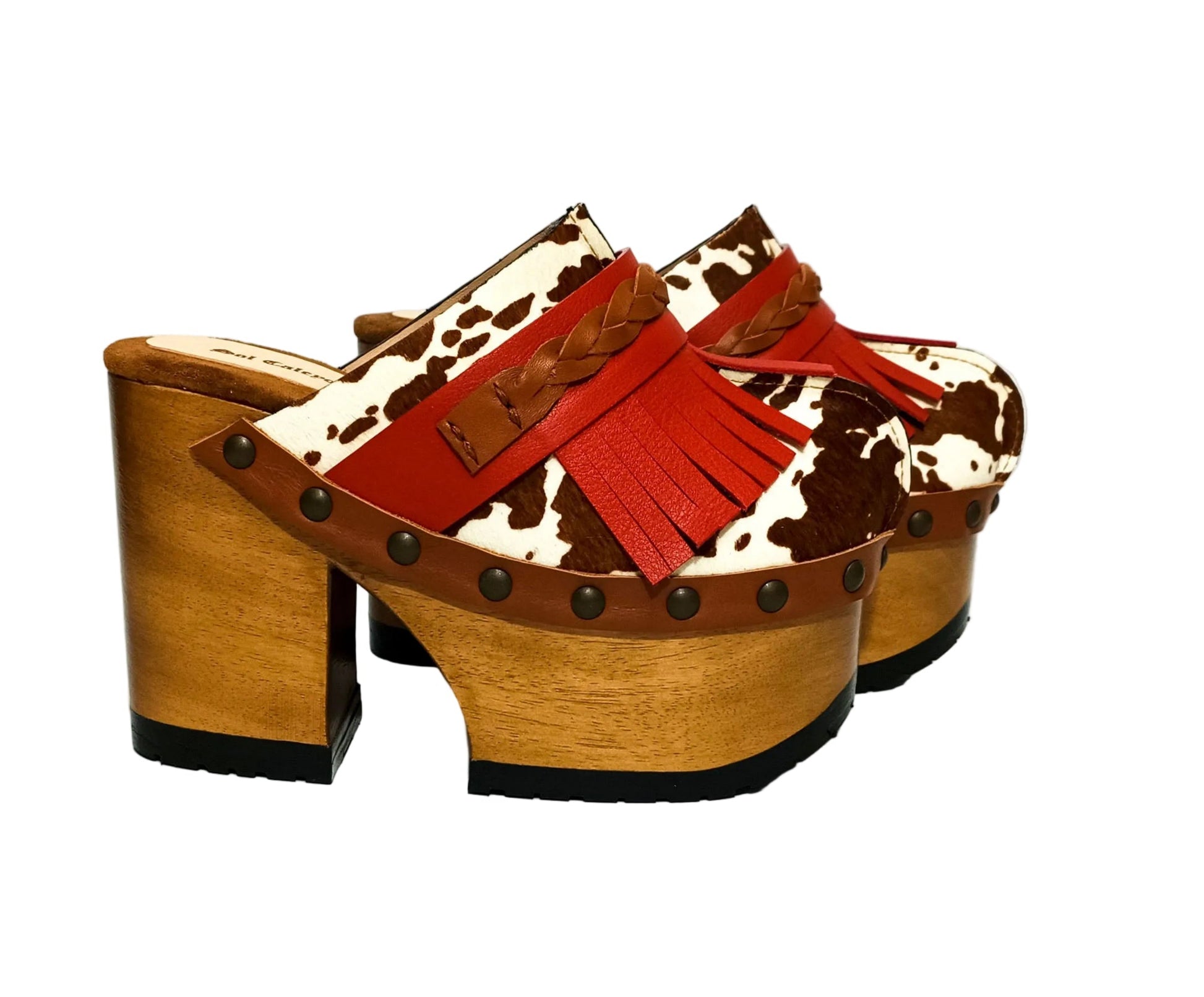 Verona Clogs by Sol Caleyo featuring light brown cow hair leather, red fringe details, and old gold studs on a high wooden platform sole with tractor grip.