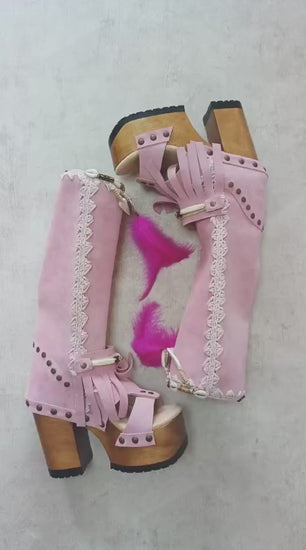 Close-up of Rhapsody Bohemia Pink Boots in premium pink suede with fringe, hand-selected feathers, and organic shells. These artisanal boho boots by Sol Caleyo feature a high hand-sculpted wooden heel and platform.