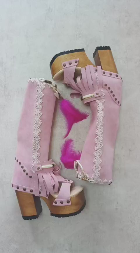 Close-up of Rhapsody Bohemia Pink Boots in premium pink suede with fringe, hand-selected feathers, and organic shells. These artisanal boho boots by Sol Caleyo feature a high hand-sculpted wooden heel and platform.