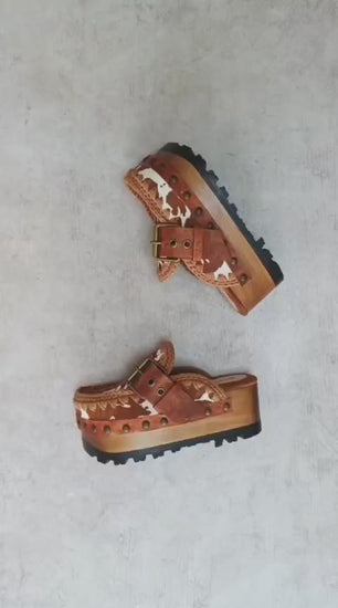 Oxford Clogs Cowhide Print by Sol Caleyo: handmade wooden platform clogs with cowhide hair-on leather, crochet trim, and aged camel leather strap.