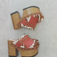 Verona Clogs by Sol Caleyo featuring light brown cow hair leather, red fringe details, and old gold studs on a high wooden platform sole with tractor grip.