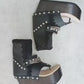 Sol Caleyo Texas Boots: Handcrafted black leather platform flip-flop sandals with wooden wedge heel, silver pyramid studs, and decorative chains. 9cm heel with zig-zag rubber traction sole.