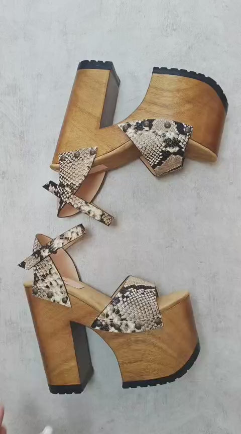 Side view of Crazy Snake Sandals by Sol Caleyo, featuring a 17 cm wooden heel, python print leather, and gold stud details on a white background.