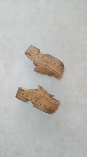 Side profile of Sol Caleyo Niza Clogs in light brown leather, showcasing hand-braided strap, crochet trim, bronze studs, and a sturdy wooden platform sole.