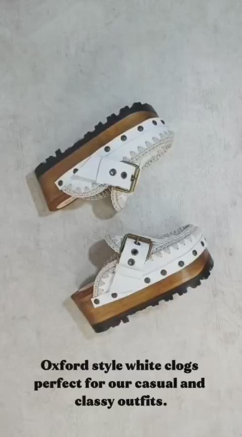 White wooden wedge clogs. White leather mules. Oxford style buckle clogs. High quality handmade shoes by Sol Caleyo.