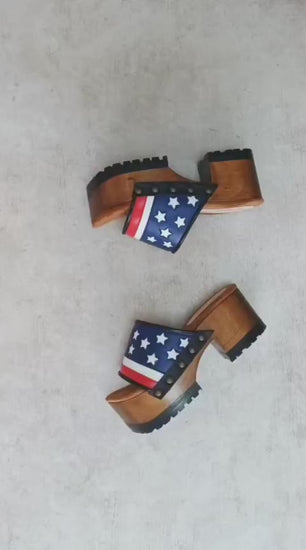 American Sandals XS by Sol Caleyo: close-up of handmade wooden platform sandals with USA flag leather strap and studs.