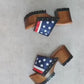 American Sandals XS by Sol Caleyo: close-up of handmade wooden platform sandals with USA flag leather strap and studs.