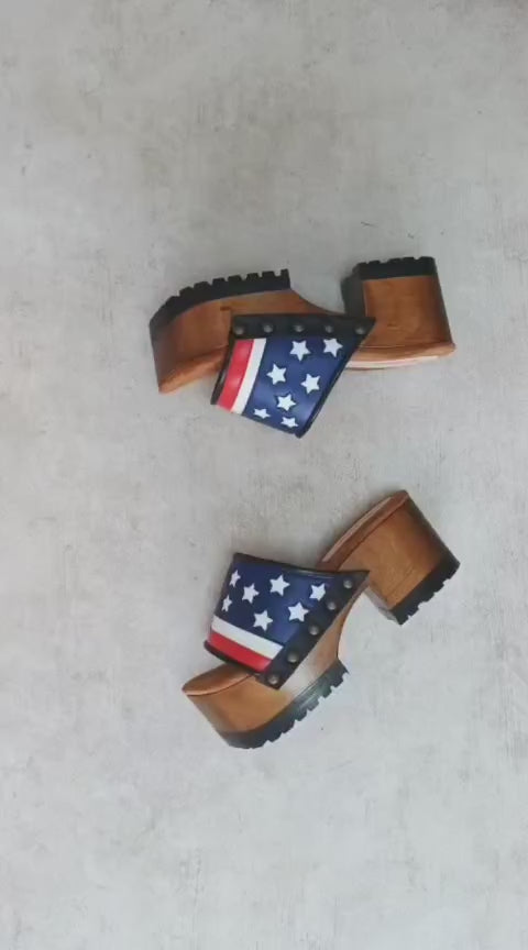 American Sandals XS by Sol Caleyo: close-up of handmade wooden platform sandals with USA flag leather strap and studs.