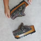 Handcrafted military camouflage and brown leather platform clog with unique crochet stitch edging and antique gold buckle detailing on a sturdy wooden base with a rugged black rubber outsole.
