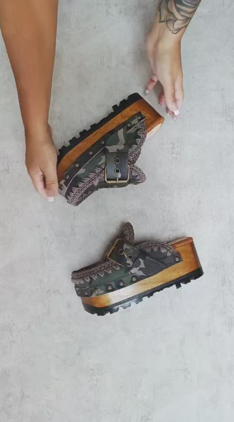 Handcrafted military camouflage and brown leather platform clog with unique crochet stitch edging and antique gold buckle detailing on a sturdy wooden base with a rugged black rubber outsole.