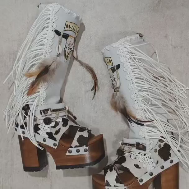 Handmade cowboy boots, white boots with cowhide and fringes. Cowboy style boots with hand painted buffalo, feathers, coins and natural shells. Vintage style platform boots. High-end leather footwear handmade by Sol Caleyo