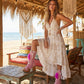 A model wearing the Rhapsody Bohemia Pink Boots at a rustic beach bar. The vibrant pink suede and bohemian details stand out against the sun-drenched wooden deck and coastal decor, embodying a free-spirited summer style.