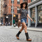 Model wearing Alabama Flip Flops Black Boots in a boho-rock style, featuring black leather platform sandals with gold studs, paired with an edgy artisanal outfit.