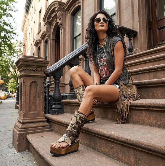 Model wearing Alabama Flip Flops Snake Boots with exotic snake-print leather, featuring a boho-chic luxury style with gold pyramid studs and high platform wedges.