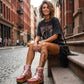 Model wearing the Kenya Flip Flop Pink Boots by Sol Caleyo, featuring metallic pink leather and high wooden platforms in a bright, edgy summer outfit.