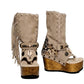 Atenea Flip Flop Boots by Sol Caleyo in neutral beige suede, featuring boho fringes, shell decorations, snake-print heel, and a tall wooden platform sole.