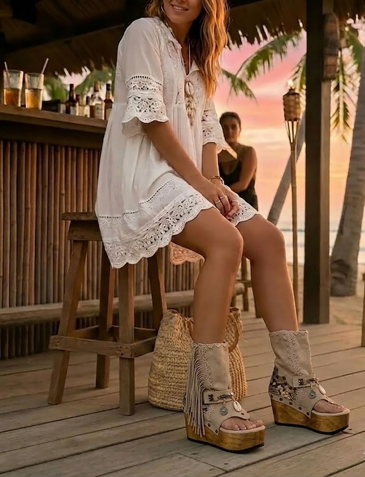 Model at a beach club wearing Atenea beige suede platform boots, showing the natural earthy tones and bohemian details in a sophisticated summer sunset setting