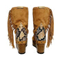Handmade Atenea Camel Flip Flop Boots by Sol Caleyo, featuring warm camel-colored suede, bohemian fringes, shell embellishments, snake-print details, and a high wooden platform sole on a white background.