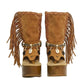 Handmade Atenea Camel Flip Flop Boots by Sol Caleyo, featuring warm camel-colored suede, bohemian fringes, shell embellishments, snake-print details, and a high wooden platform sole on a white background.