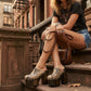 Model walking in New York City wearing the exotic Tokio Snake Clogs by Sol Caleyo, showcasing the python-print leather and high wenge platform against an urban brownstone backdrop.