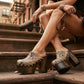 Model walking in New York City wearing the exotic Tokio Snake Clogs by Sol Caleyo, showcasing the python-print leather and high wenge platform against an urban brownstone backdrop.