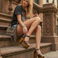 Model wearing the Crazy Brown Sandals by Sol Caleyo, highlighting the secure ankle strap and the dramatic height of the dark wood platform for a bold, artisanal look.