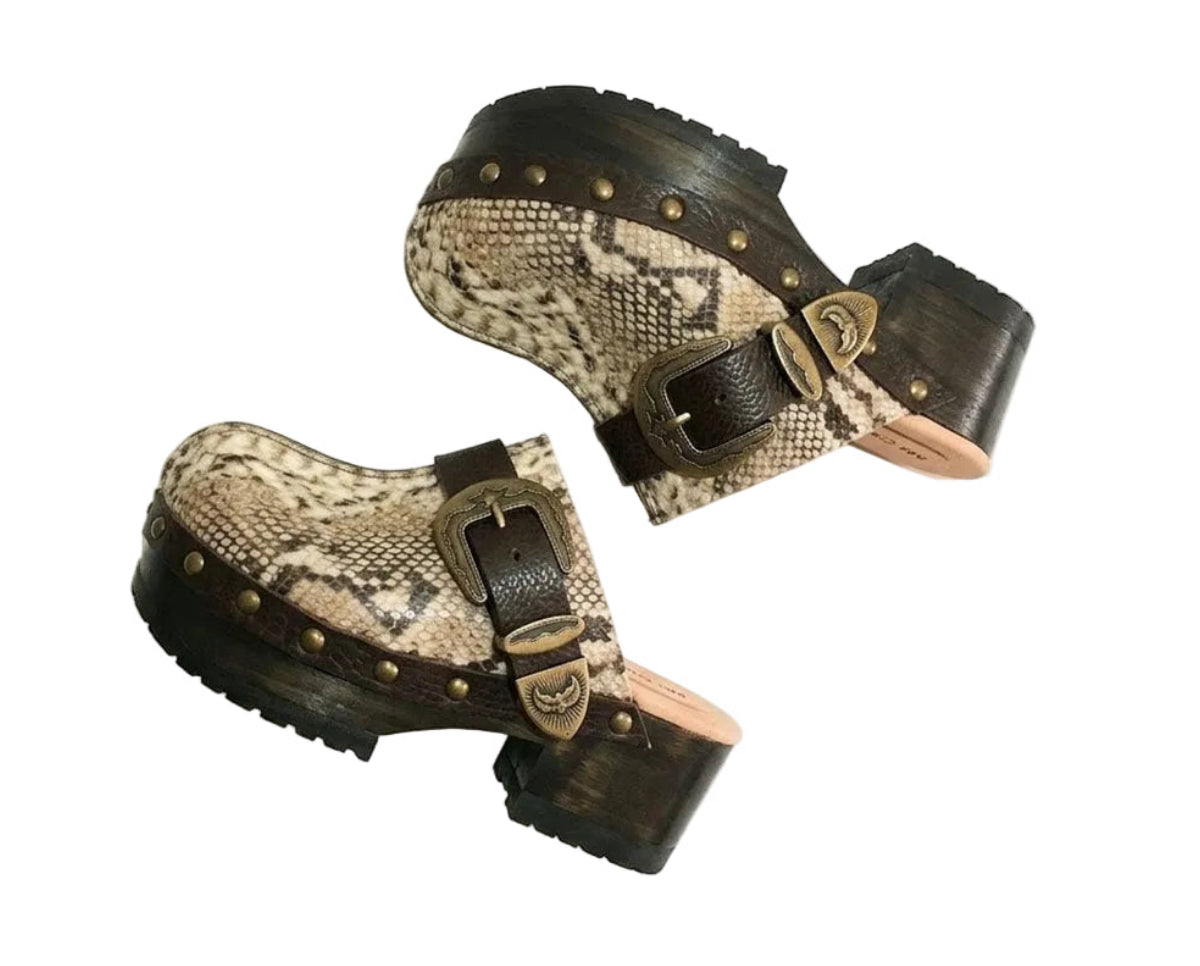 Handmade snake print leather clogs with brown leather strap and antique gold buckle on a wooden platform sole.