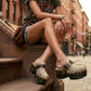Fashion model wearing Sol Caleyo Route 66 snake print platform clogs with denim shorts and a vintage t-shirt on city steps.