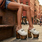 Close-up of a model wearing Sol Caleyo White Indian Clogs XL with 17cm heels and metal conchos, styled with denim shorts in an urban setting.