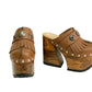 Side profile of Sol Caleyo Light Brown Indian Clogs XL featuring a high 17cm wooden platform, textured brown leather, decorative fringes, and antique metal conchos on a white background.