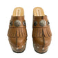 Side profile of Sol Caleyo Light Brown Indian Clogs XL featuring a high 17cm wooden platform, textured brown leather, decorative fringes, and antique metal conchos on a white background.