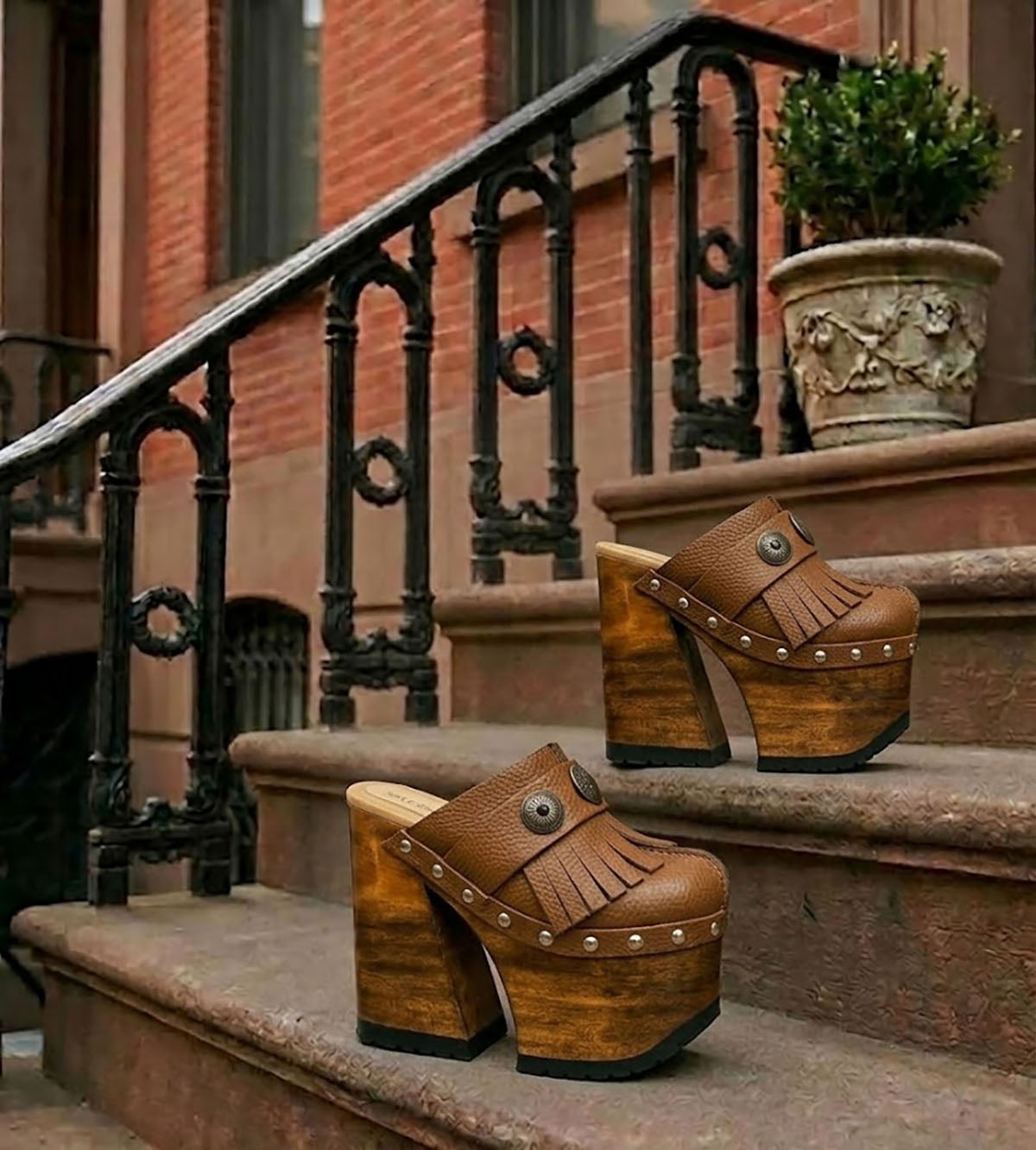 Side profile of Sol Caleyo Light Brown Indian Clogs XL featuring a high 17cm wooden platform, textured brown leather, decorative fringes, and antique metal conchos on a white background.