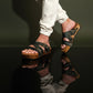 Man wearing handmade camouflage leather wooden sole sandals outdoors, showing fit and rugged style.