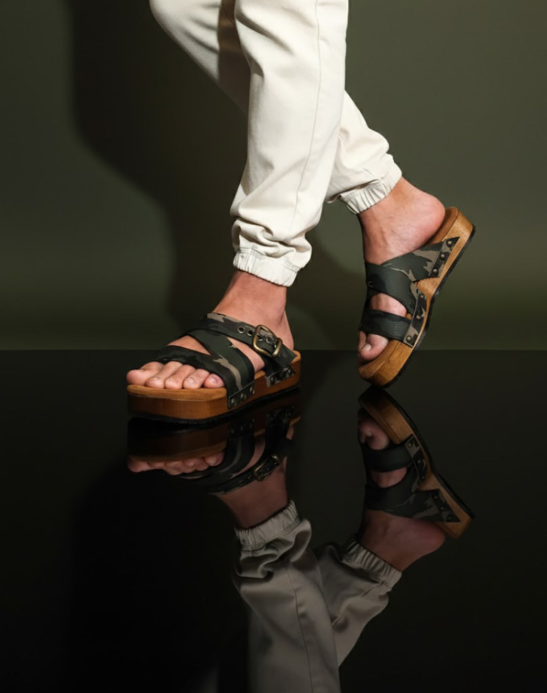 Man wearing handmade camouflage leather wooden sole sandals outdoors, showing fit and rugged style.