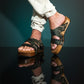 Man wearing handmade camouflage leather wooden sole sandals outdoors, showing fit and rugged style.