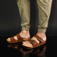 Man wearing handmade brown leather wooden sole sandals outdoors, showing fit and rugged style.