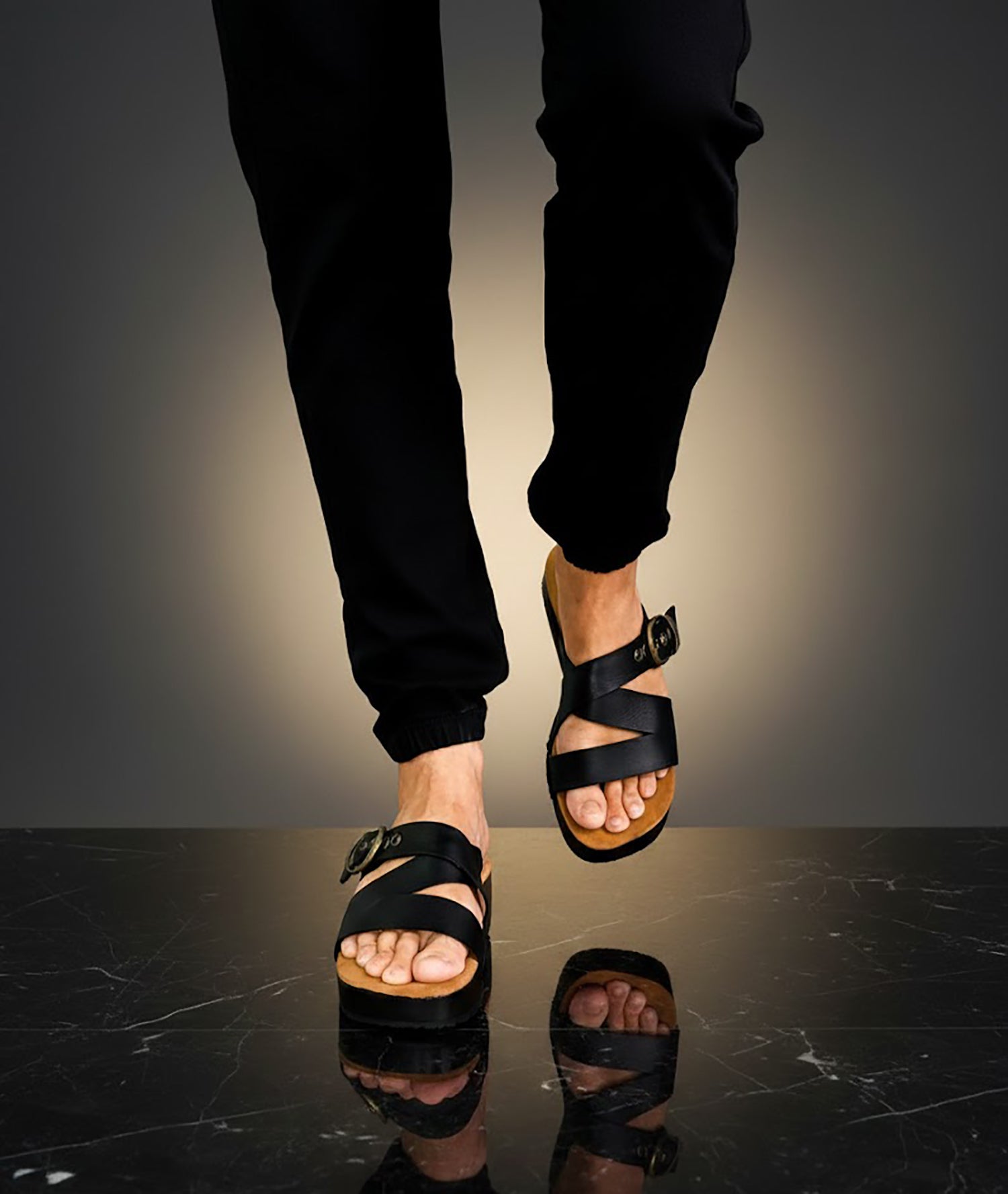 Man wearing handmade black leather wooden sole sandals outdoors, showing fit and rugged style.