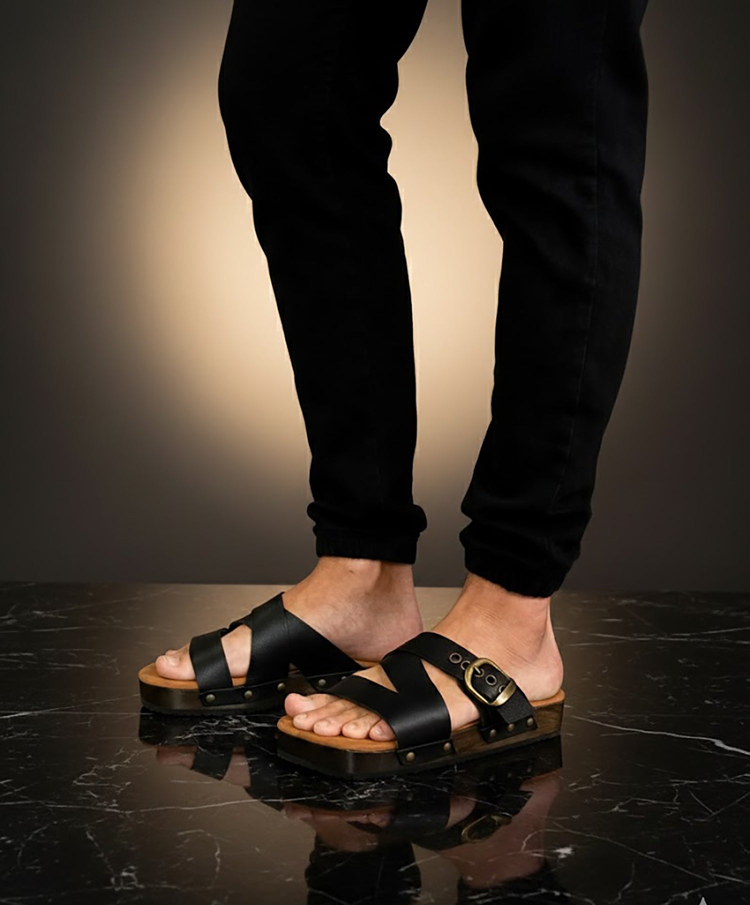 Man wearing handmade black leather wooden sole sandals outdoors, showing fit and rugged style.